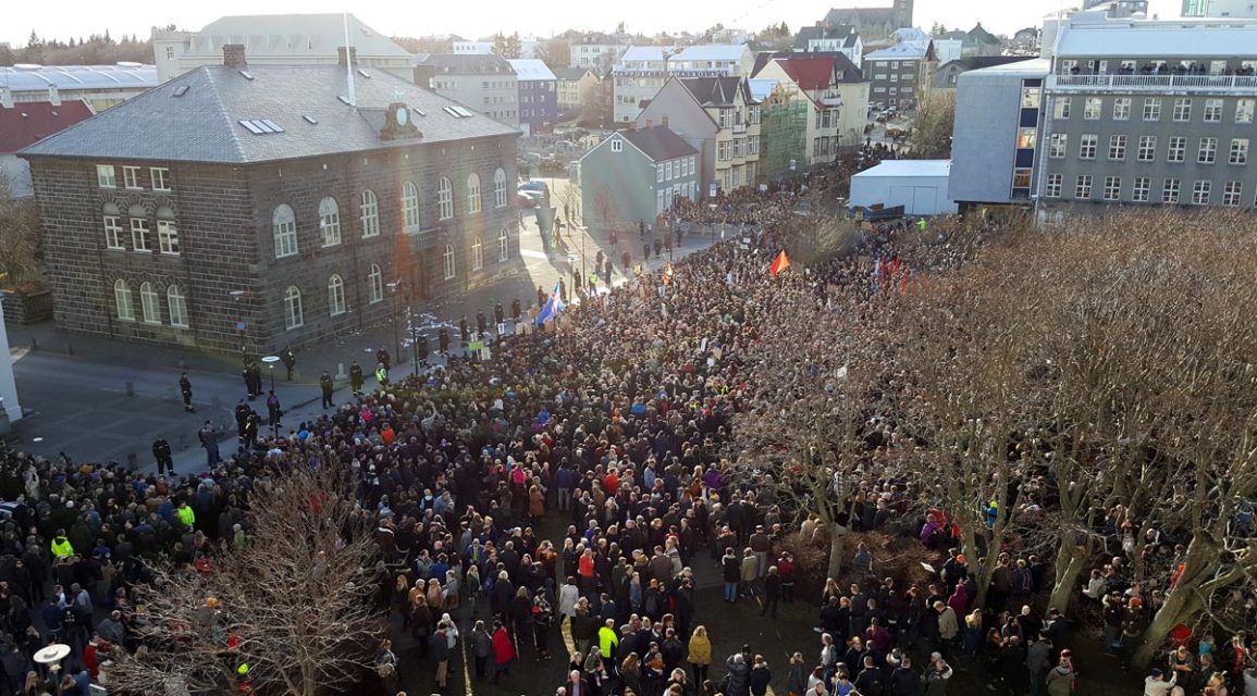 Wide shot of a large crowd in front of Iceland's parliament building.