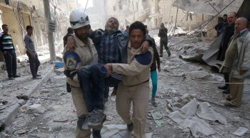 Emergency personnel carry an injured man following reported air strikes by government forces on Aleppo in March 2015