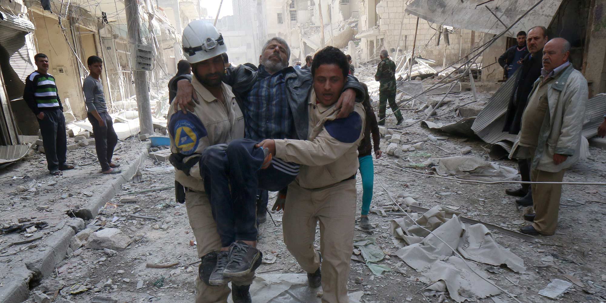 Emergency personnel carry an injured man following reported air strikes by government forces on Aleppo in March 2015