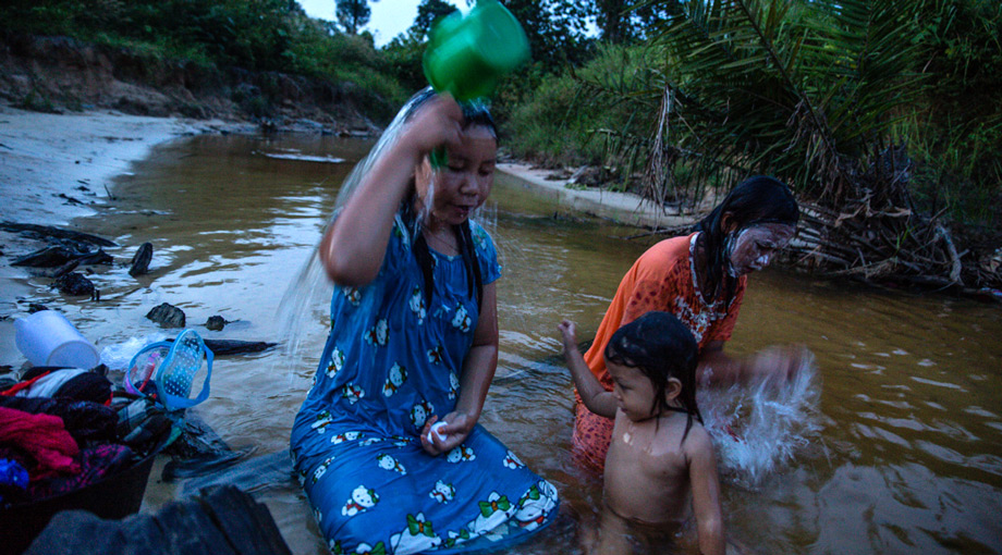 Locals bathe in the river next to the area where 35 homes were destroyed by police and personnel from Asiatic Persada in 2011