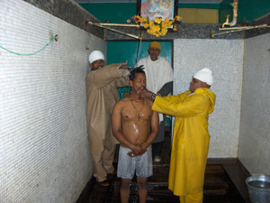 A man is showered in holy water as Atnafu Betseha, an Orthodox priest, imposes a large iron cross on him