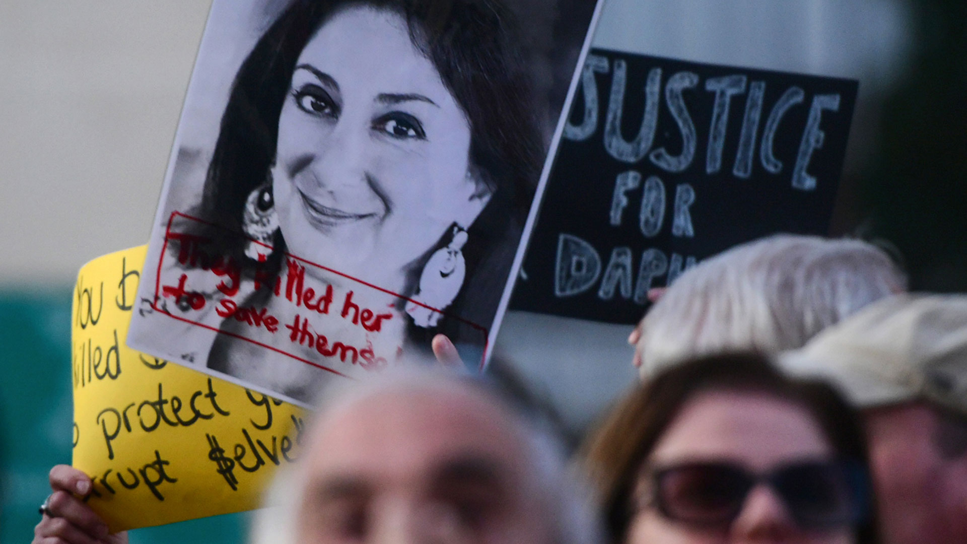 Protesters hold Daphne Caruana Galizia signs in Malta