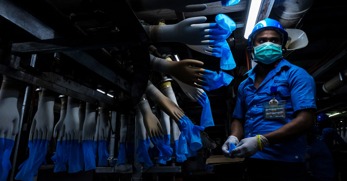 An employee monitors latex gloves on hand-shaped molds moving along an automated production line at a Top Glove Corp. factory in Malaysia