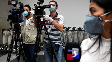 Journalists in Colombia wear protective face masks