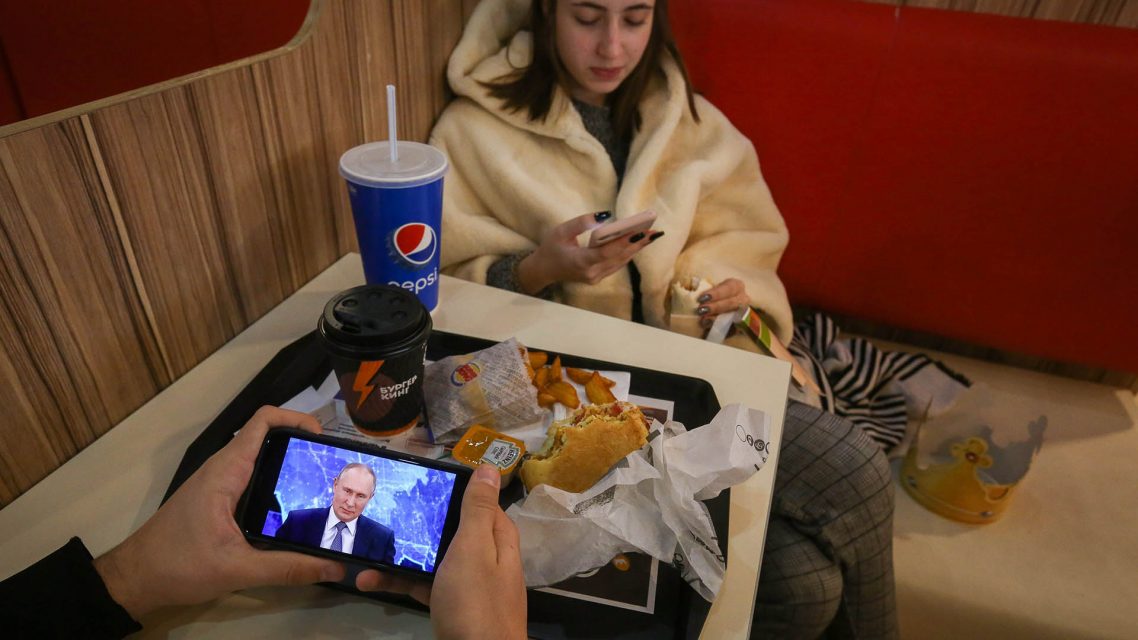 Photo of a Burger King customer watching a Putin press conference on their phone.