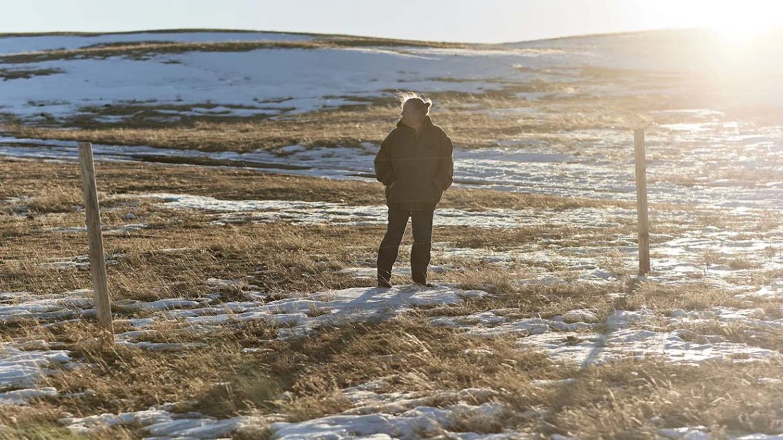 Photo of Melodie Hill standing in a field on the prairie