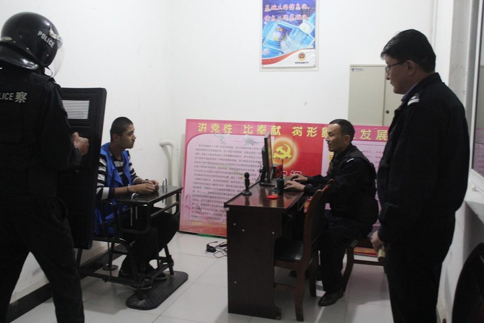 Photo showing man chained to chair surrounded by guards