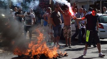 Photo showing protesters near a fire with flares