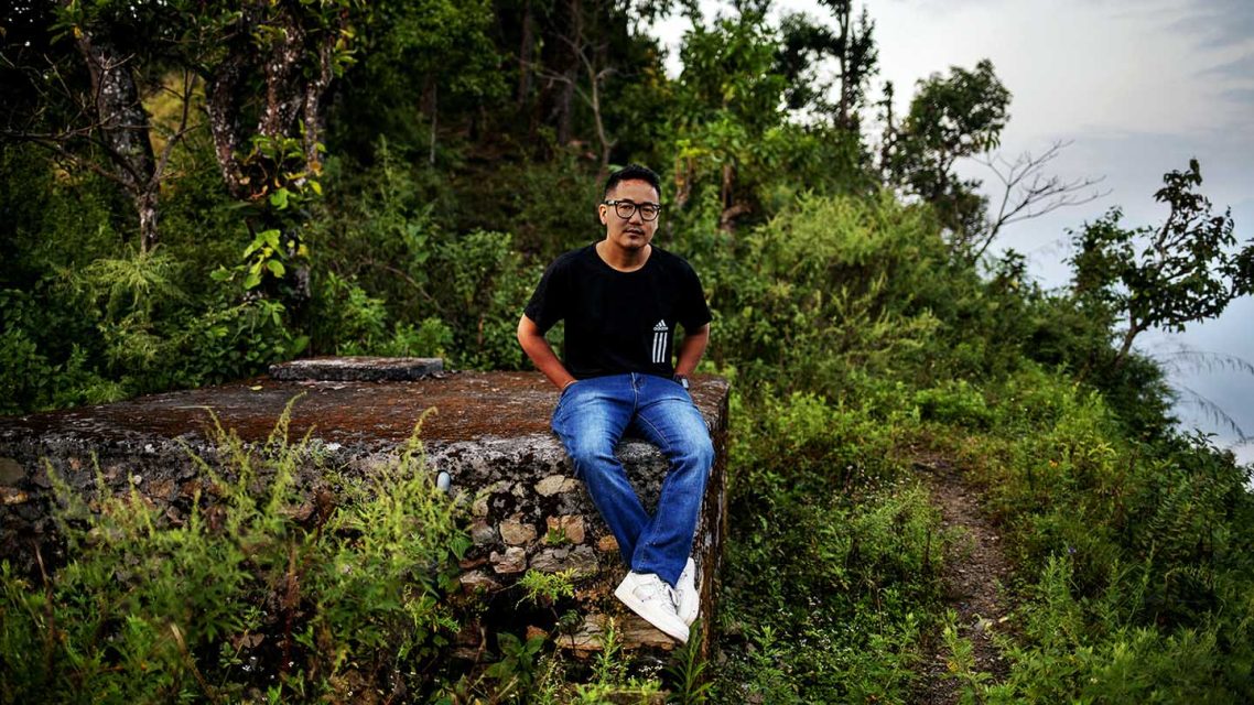 Photo of Dilip Gurung sitting in a forest near his home in Nepal