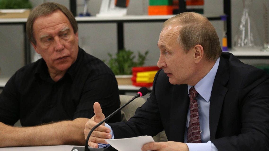 Photo of Roldugin looking on as Putin speaks