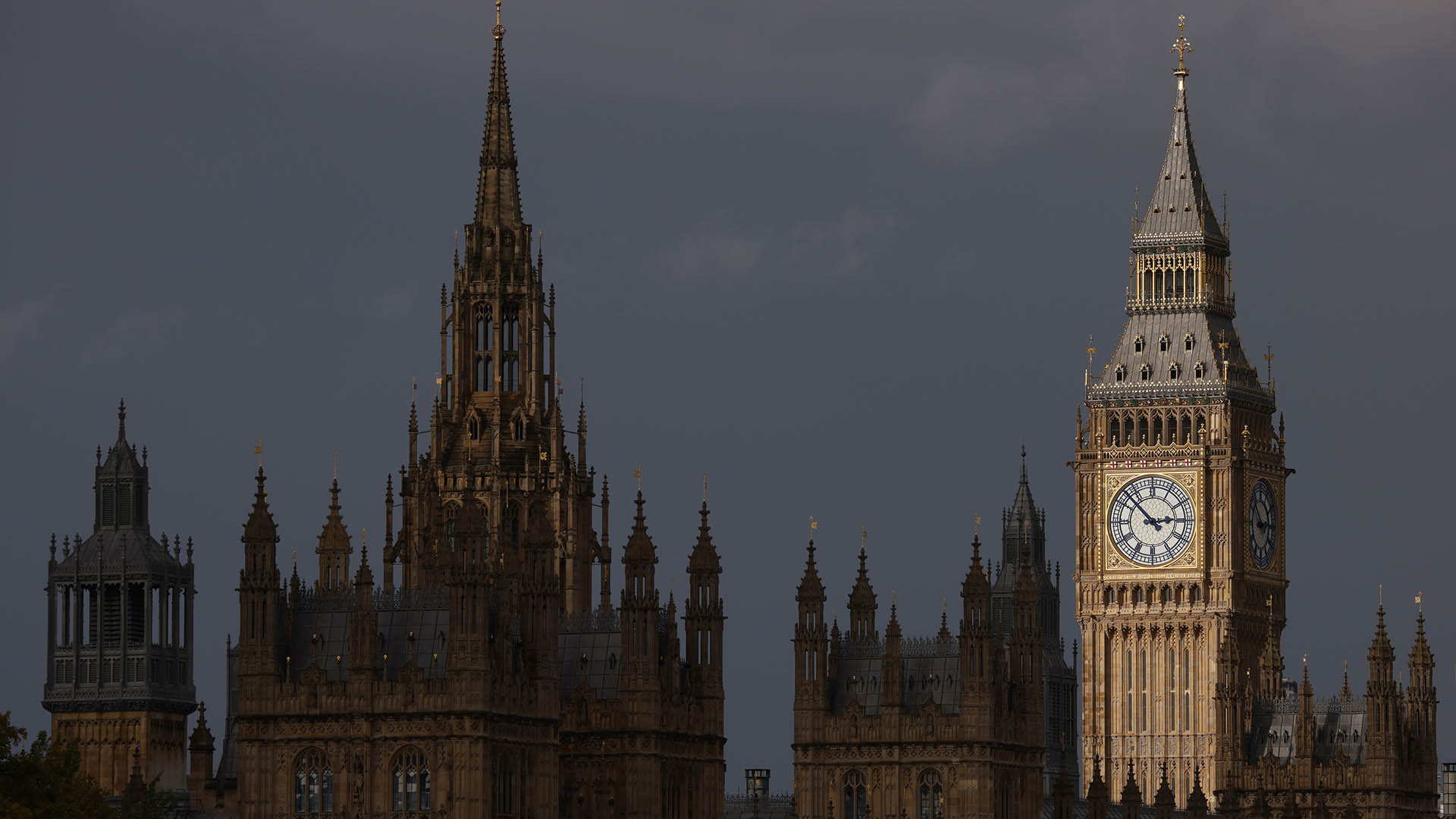 A photo of U.K. parliament with Big Ben illuminated and the rest of the building in shadow