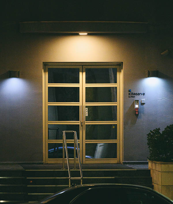Night photo of a well-lit office door surrounded by shadows with a Kiteserve nameplate beside the door.