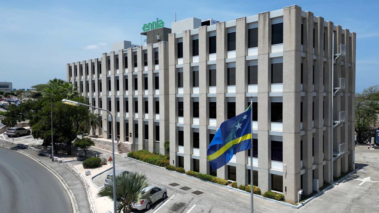 A five-storey gray office building with a green Ennia sign on top.