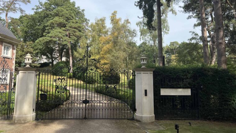 A picture of a gate in front of a mansion