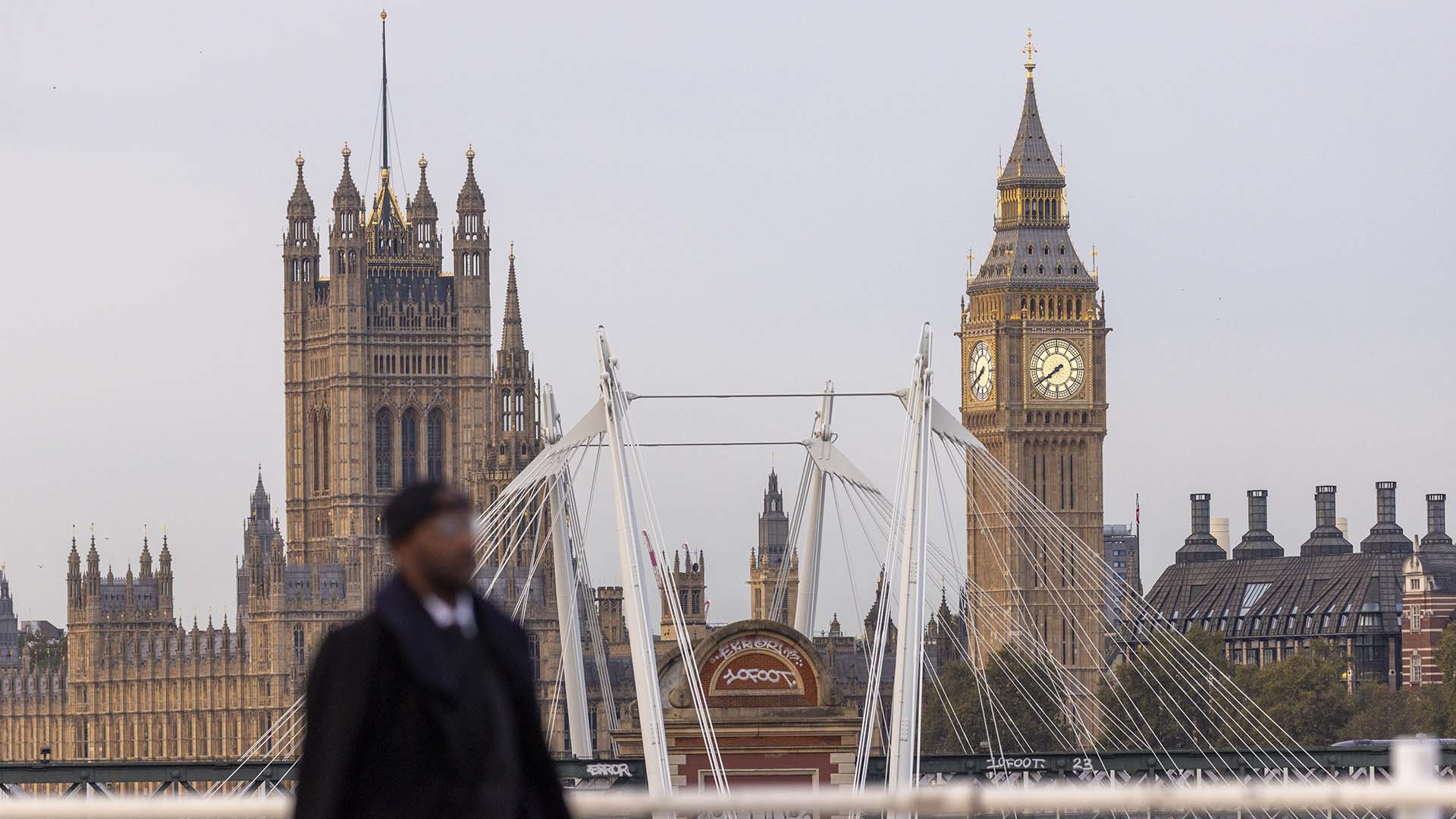 A commuter crosses Waterloo Bridge in view of the Houses of Parliament in London