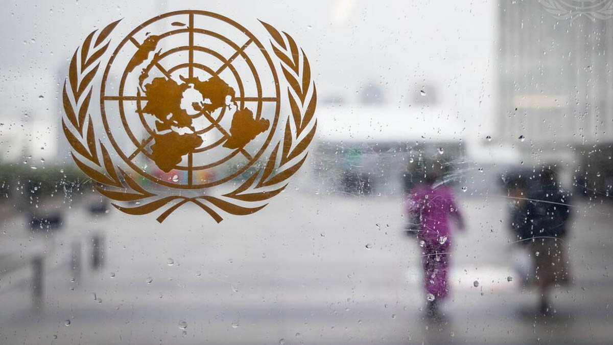 United Nations emblem on a window, with blurred people in the background.