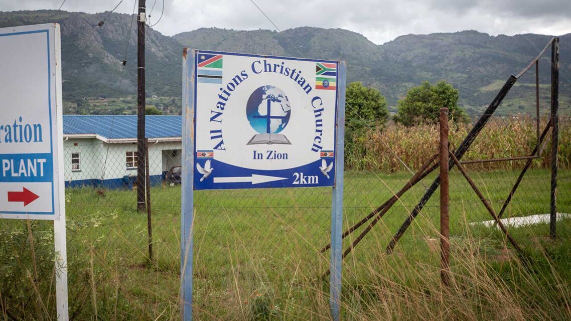 Sign reading All Nations Christian Church In Zion, 2km to the right