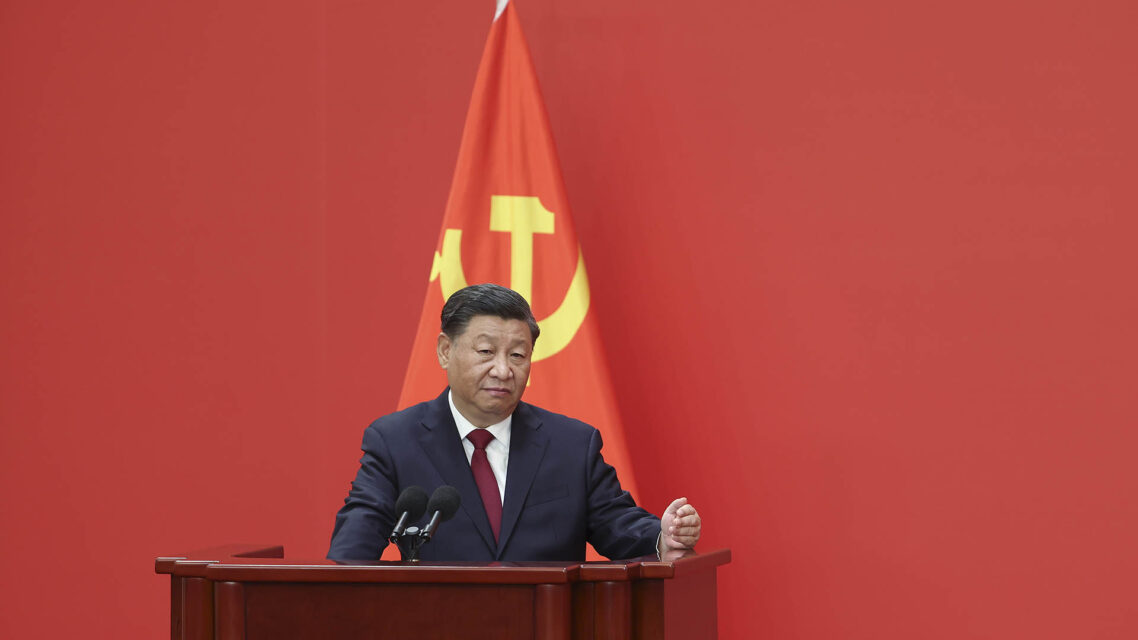 Photo of Xi Jinping in front of a Chinese flag.