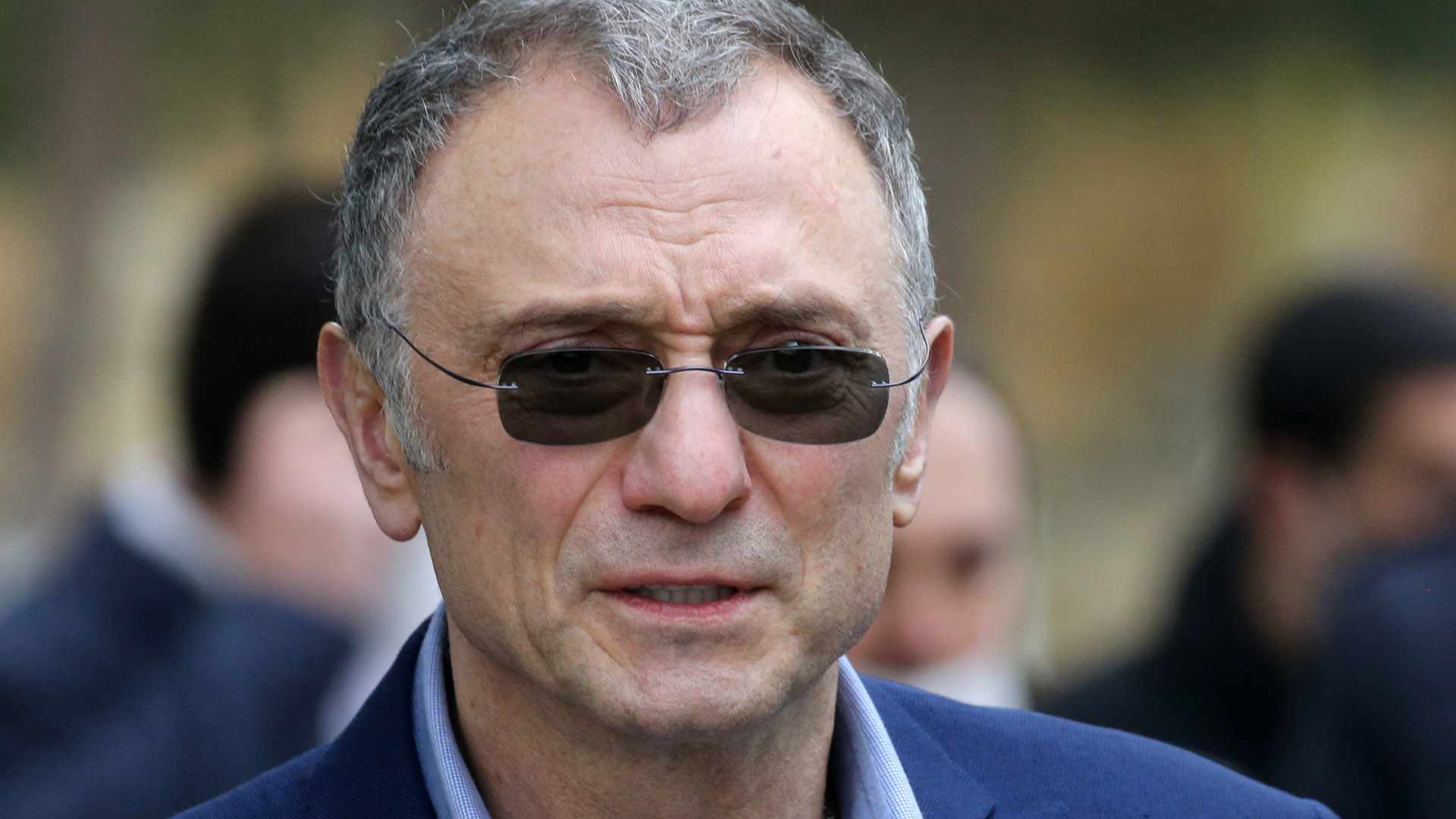 A man with grey hair wearing sunglasses and a suit