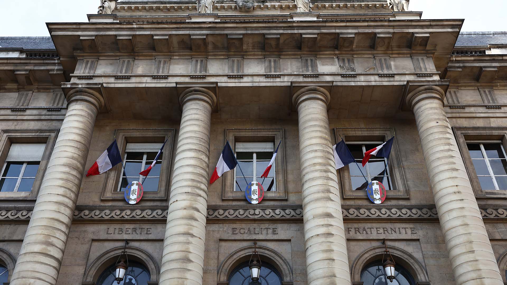Photo of French flags hanging outside the Palais de Justice building in Paris.