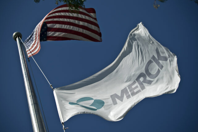 SUMMIT, NJ - OCTOBER 2: A Merck flag flies in front of the company's building on October 2, 2013 in Summit, New Jersey. The pharmaceutical company Merck & Co. announced today that it would cut 8,500 jobs and consolidate its real estate in Kenilworth, New Jersey instead of moving its headquarters to Summit as previously planned. 