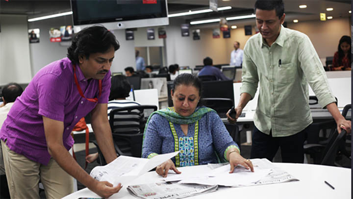 Reporters P Vaidyanathan Iyer, Ritu Sarin, Jay Mazoomdaar examining papers on a desk.