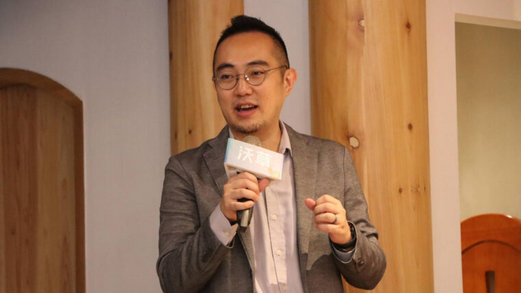 A man with glasses talks into a microphone