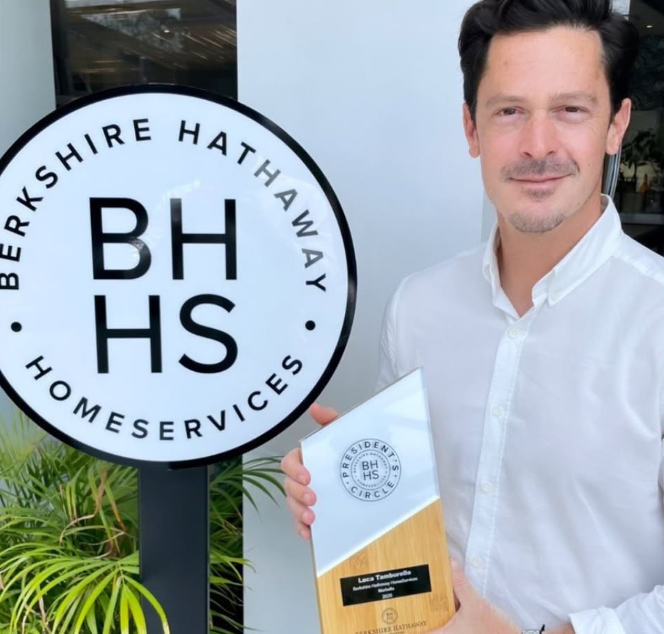 Photo of Luca Tamburello standing beside a sign that reads Berkshire Hathaway Home Services.