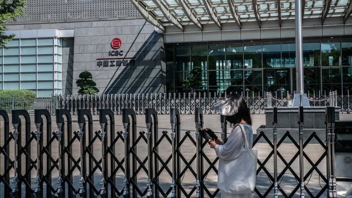 Photo of a woman walking past a building with an ICBC sign in Beijing.