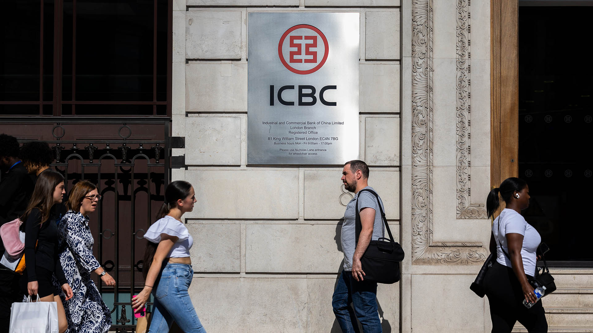 Photo of people walking past a building with a sign that reads ICBC
