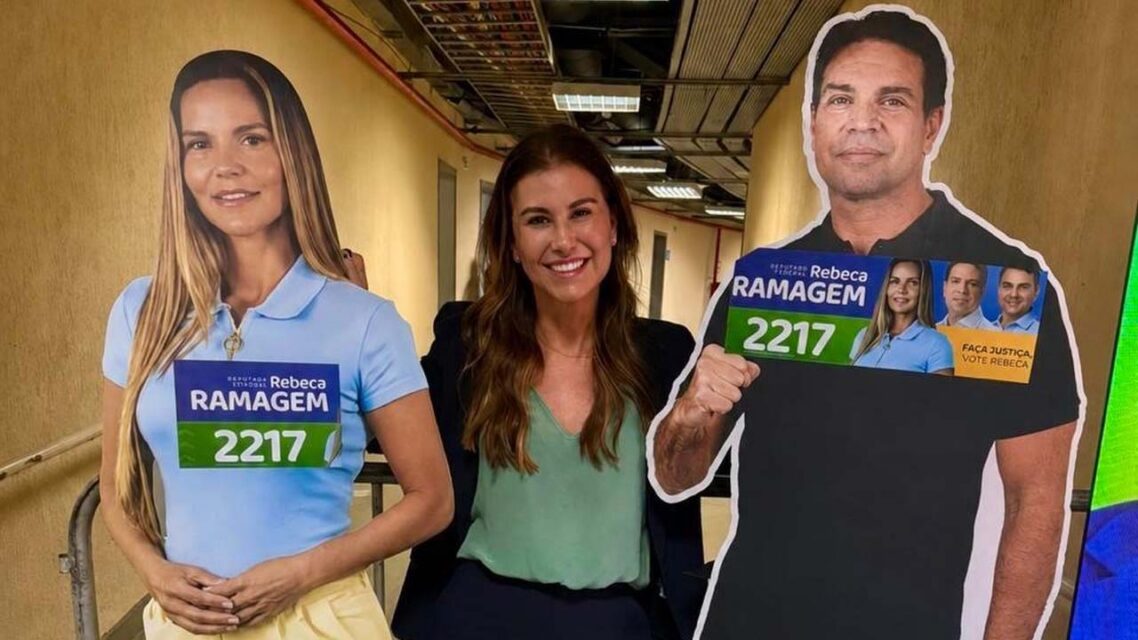 Photo of Fernanda Bolsonaro standing between two life-size cardboard cutouts of Rebeca and Alexandre Ramagem.